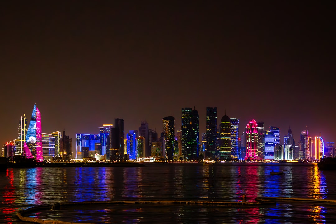 The Doha, Qatar skyline lit up at night, viewed across the water.